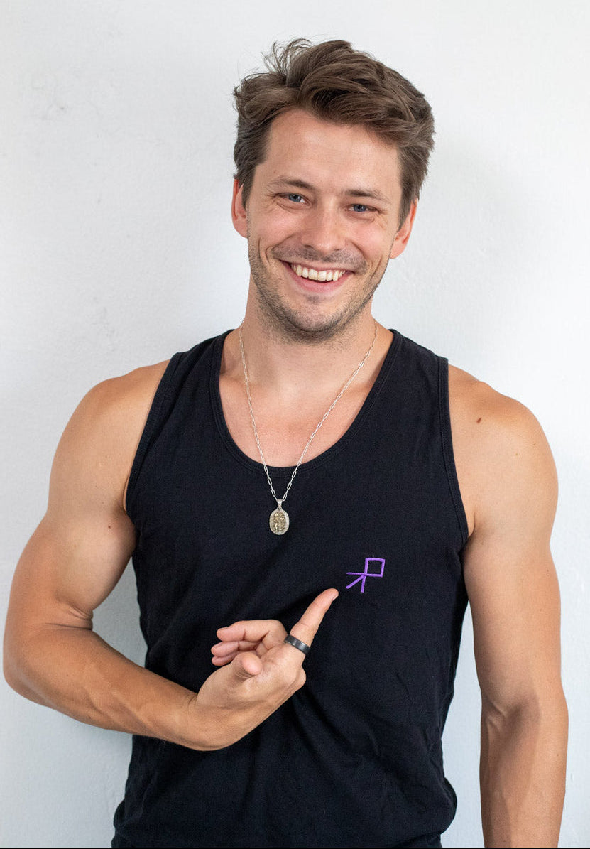 Man wearing a black tank top with a small Push Pass Whip logo, smiling against a white background